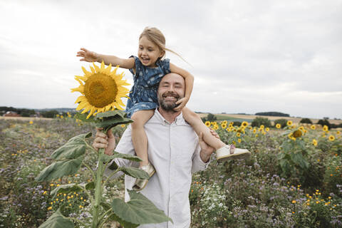 Glücklicher Mann mit Tochter in einem Sonnenblumenfeld, lizenzfreies Stockfoto