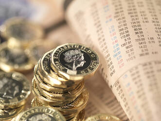 Finanzen und Wirtschaft im Vereinigten Königreich, britische Pfundmünzen auf einer Seite mit den Aktienkursen von Finanzzeitungen - ABRF00573