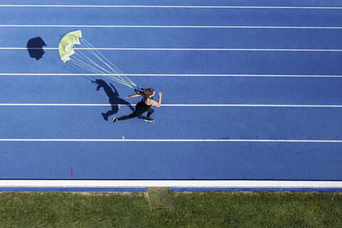 Draufsicht auf eine Läuferin mit Fallschirm auf der Tartanbahn, lizenzfreies Stockfoto