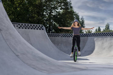 Junge Frau fährt Einrad im Skatepark - STSF02211