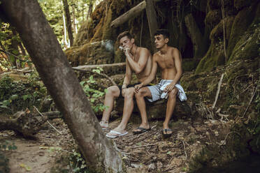 Two barechested friends smoking a joint of marijuana in nature - ACPF00628