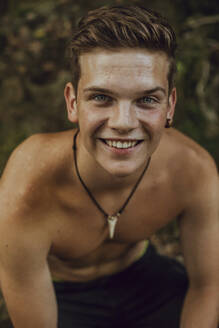Porträt eines lächelnden barbusigen jungen Mannes in der Natur - ACPF00636
