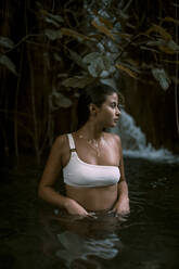 Junge Frau in einem See mit einem Wasserfall im Hintergrund - ACPF00640