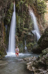 Junge Frau posiert an einem Wasserfall - LJF00904