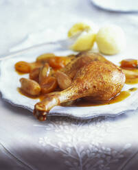 Close-up of roasted goose leg with apricots and shallots served in plate on table - PPXF00275