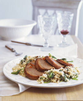 Close-up of roasted goose breast with risotto and spinach served in plate on table - PPXF00277