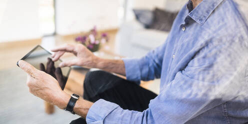 Close-up of senior man using tablet at home - SBOF01986