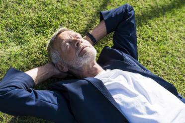 Senior businessman lying in grass with closed eyes - SBOF02026