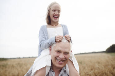 Portrait of senior man carrying granddaughter on his shoulders in nature - EYAF00415