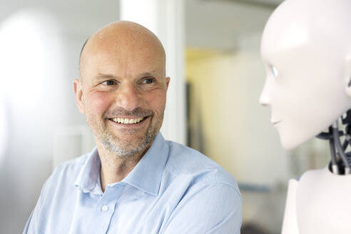 Portrait of smiling businessman looking at robot - KSHSF00003