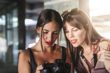 Zwei junge Frauen prüfen Fotos auf einer Kamera - LJF00915