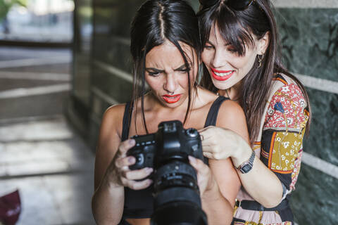 Zwei junge Frauen prüfen Fotos auf einer Kamera, lizenzfreies Stockfoto