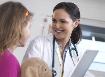 Female doctor showing a young female patient her lab results on a digital tablet in the clinic - ABRF00575