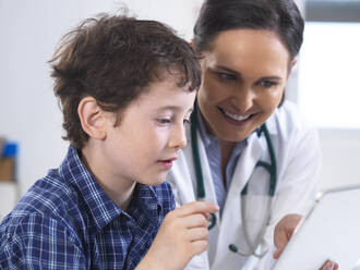 Eine Ärztin zeigt einem jungen männlichen Patienten seine Laborergebnisse auf einem digitalen Tablet in der Klinik - ABRF00576