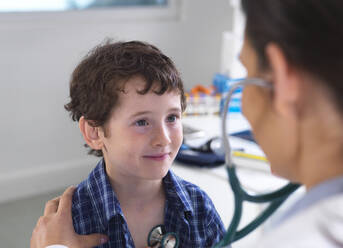 Female doctor examiming a boy using a stethoscope - ABRF00579