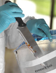 Forensic scientist bagging a knife taken from a violent crime scene - ABRF00596