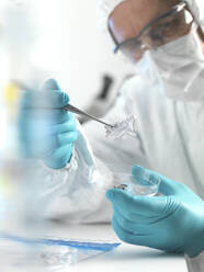 Forensic scientist examining fragments of paper in a laboratory - ABRF00598