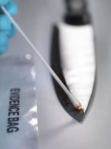 Gerichtsmedizinerin nimmt DNA-Beweise von einem blutverschmierten Messer auf, lizenzfreies Stockfoto