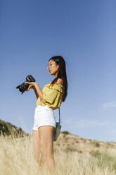 Junge Frau mit Kamera in abgelegener Landschaft, Granada, Spanien - LJF00950