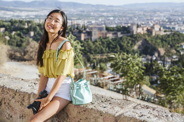 Lächelnde junge Frau mit Kamera in der Alhambra, Granada, Spanien - LJF00966