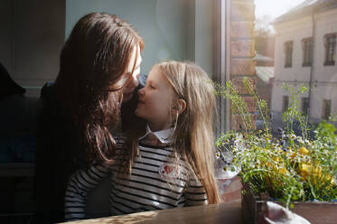 Smiling girl with her mother in a cafe - EYAF00435