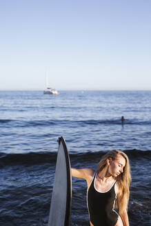 Female teenager with surfboard at the sea - LJF00974