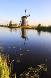 Typische Windmühlen, die sich in der Gracht spiegeln, umrahmt von Gras im Frühling, Kinderdijk, UNESCO-Weltkulturerbe, Molenwaard, Südholland, Niederlande, Europa - RHPLF07811