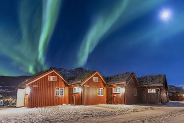 Das Nordlicht (Aurora Borealis) und der Mond beleuchten typische Holzhütten namens Rorbu, Manndalen, Kafjord, Lyngen Alps, Troms, Norwegen, Skandinavien, Europa - RHPLF07942