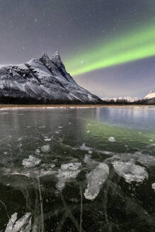 Eisblasen auf dem gefrorenen Meer und der verschneite Gipfel des Otertinden unter dem Nordlicht (Aurora Borealis), Oteren, Lyngen Alps, Troms, Norwegen, Skandinavien, Europa - RHPLF07943