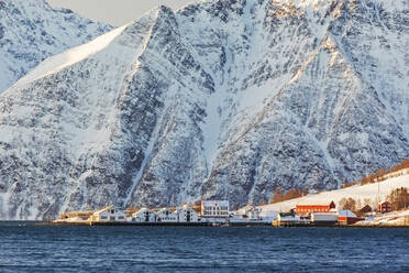 Das typische Fischerdorf Hamnes, eingerahmt von schneebedeckten Gipfeln und dem kalten Meer, Lyngen Alps, Troms, Norwegen, Skandinavien, Europa - RHPLF07951
