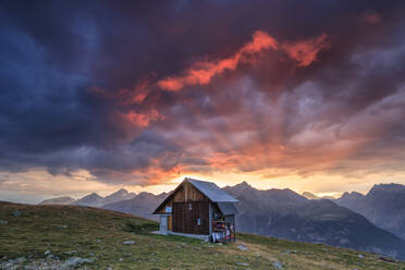 Holzhütte eingerahmt von feurigem Himmel und Wolken bei Sonnenuntergang, Muottas Muragl, St. Moritz, Kanton Graubünden, Engadin, Schweiz, Europa - RHPLF07958