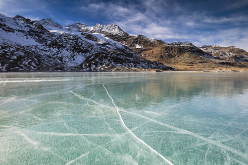 Die schneebedeckten Gipfel umrahmen das gefrorene türkisfarbene Wasser des Weißen Sees (Lago Bianco), Berninapass, Kanton Graubünden, Engadin, Schweiz, Europa - RHPLF07962