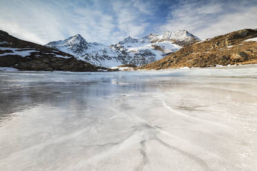 Blauer Himmel und Wolken auf dem gefrorenen Lej Nair, umgeben von verschneiten Gipfeln, Berninapass, Kanton Graubünden, Engadin, Schweiz, Europa - RHPLF07963