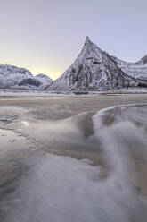 Schneebedeckte Gipfel und Sandstrand eingerahmt von den eisigen Wellen des gefrorenen Meeres in der Morgendämmerung, Ersfjord, Senja, Troms, Norwegen, Skandinavien, Europa - RHPLF08066