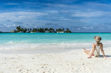 Frau sitzt an einem weißen Sandstrand und genießt das türkisfarbene Wasser, Sun Island Resort, Insel Nalaguraidhoo, Ari-Atoll, Malediven, Indischer Ozean, Asien - RHPLF08076