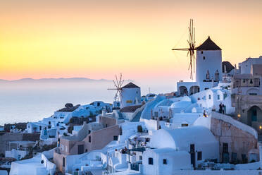 Sunset over the white stone buildings and windmills of Oia on the tip of Santorini's caldera, Santorini, Cyclades, Greek Islands, Greece, Europe - RHPLF08182