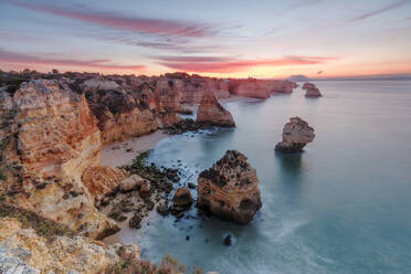 Sonnenaufgang auf den Klippen, eingerahmt vom türkisfarbenen Wasser des Ozeans, Praia da Marinha, Caramujeira, Gemeinde Lagoa, Algarve, Portugal, Europa - RHPLF08242