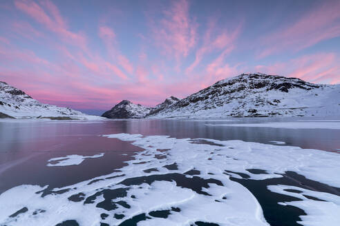 Der zugefrorene Lago Bianco umrahmt von rosa Wolken in der Morgendämmerung, Berninapass, Kanton Graubünden, Engadin, Schweiz, Europa - RHPLF08246