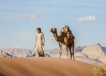 Bedouin walking with his camel, Wadi Rum, Aqaba Governorate, Jordan, Middle East - RHPLF08419