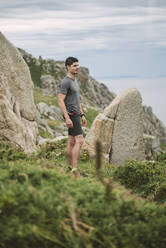 Trail runner standing in coastal landscape, Ferrol, Spain - RAEF02281