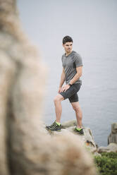 Trailrunner auf einem Felsen in Küstenlandschaft, Ferrol, Spanien - RAEF02283