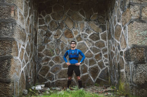 Porträt eines an einer Wand stehenden Trailrunners, lizenzfreies Stockfoto