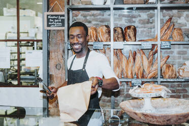 Lächelnder Mann bei der Arbeit in einer Bäckerei - JCMF00144