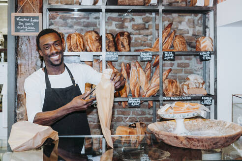 Lächelnder Mann bei der Arbeit in einer Bäckerei - JCMF00147