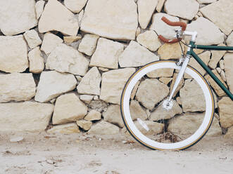 Fixie-Fahrrad an Natursteinmauer gelehnt, Teilansicht - DLTSF00044