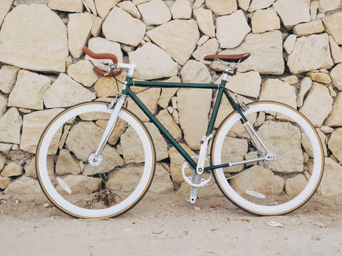 Fixie-Fahrrad lehnt an einer Natursteinmauer, lizenzfreies Stockfoto