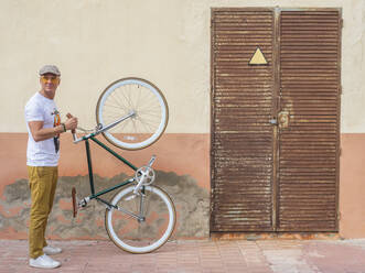 Mann mit Fixie-Fahrrad vor einer Wand stehend - DLTSF00048