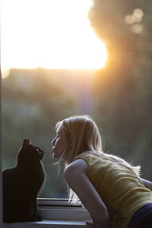 Black cat and woman in front of window at sunset - CHPF00569