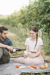 Glückliches junges Paar beim Picknick mit Prosecco in den Weinbergen - ALBF01018