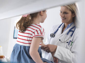 Female doctor examining and diagnosing a young girl in a clinic - ABRF00617